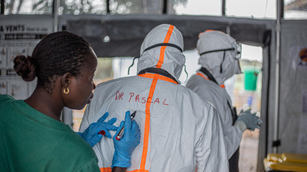 A health worker writes the name of a doctor on the back of their protective suit before entering the Ebola treatment center in Rwampara to care for patients infected with the Ebola virus disease, in Bunia (Ituri), in eastern Democratic Republic of Congo, on July 13, 2026.
